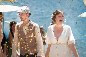 bride and groom walk down isle while confetti falls on them.
